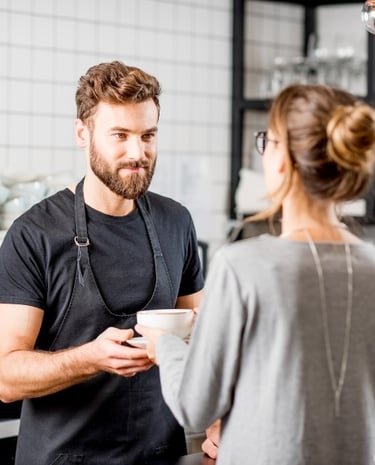 a barista handing coffee to a customer