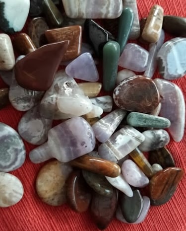 Colección de piedras semipreciosas pulidas y cristales sobre un fondo de tela roja.
