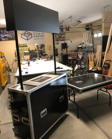 Custom black flight case trade show booth with signage and portable folding table in a workshop.
