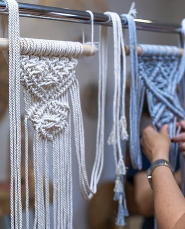 Decoraciones de tapices de macramé hechas a mano siendo elaboradas en un soporte en un taller textil