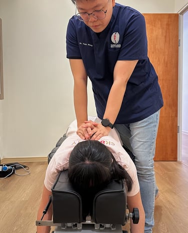 Chiropractor performing manual back adjustment on female patient at Sinisana Chiropractic clinic.