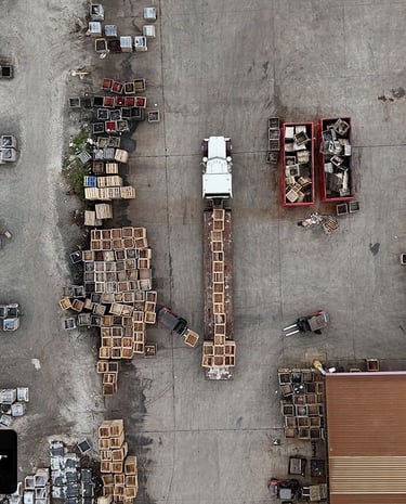 a truck parked in a parking lot getting a shipment loaded by forklifts.