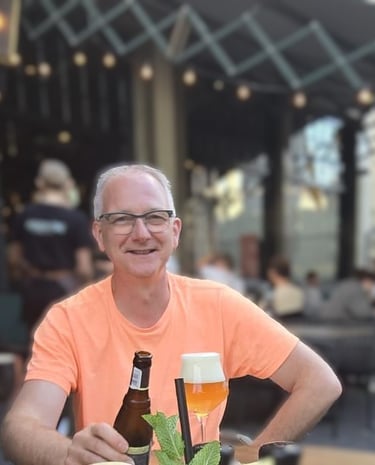Portretfoto van Joop de Pooter die bij een restaurant een drankje drinkt