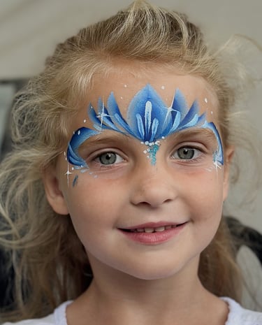 Alt-tekst: Glimmachend meisje met een blauw-wit geschminkte ijsprinsessenkroon.