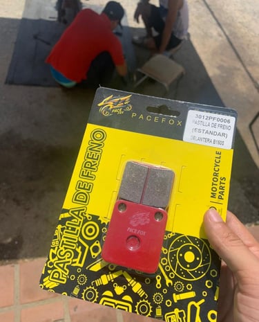 Mano sosteniendo un paquete de pastillas de freno Pacefox para motocicleta
