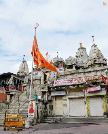 Street view of Jagdish Temple in Udaipur, showing bustling old-city lanes leading to the tall, carved shikhara.