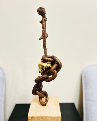 Iron sculpture with stone on wooden pedestal