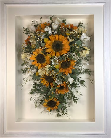 a Trailing view Style bouquet of flowers in a ridged white frame