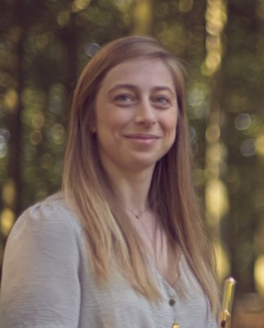 a woman holding a trumpet in a forest
