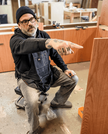 Master woodworker and artisan craftsman giving direction to team in Detroit workshop.