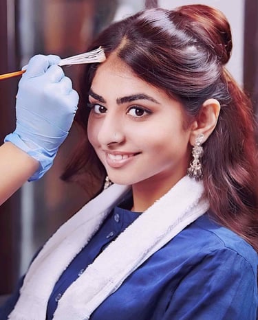 a woman in a blue shirt is getting her hair roots touched up by colors