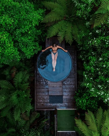 overhead view of a lady soaking in a jacuzzi in a forest