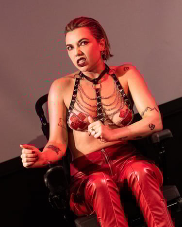 A white electric wheelchair user in red leather trousers and a black leather harness