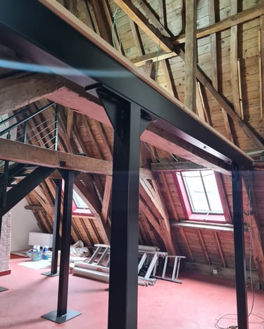 Structure métallique installée dans des combles avec charpente bois apparente – support pour mezzani