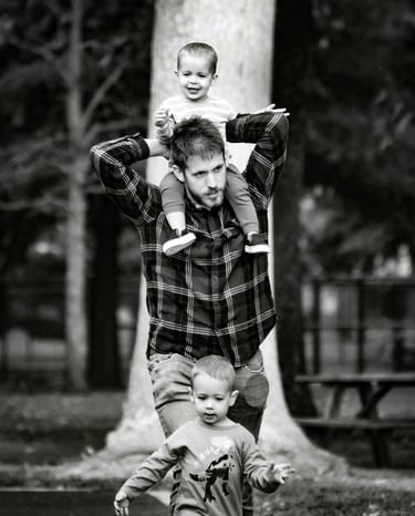 Father with one son on shoulders, other in front walking