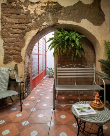 Encantador patio mexicano con entrada arqueada, piso de baldosas estampadas, sillas y plantas