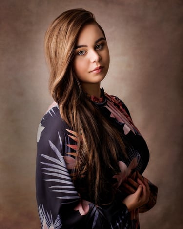 a beautiful girl posing in a photography studio, she has long light brown wavey hair and green eyes 