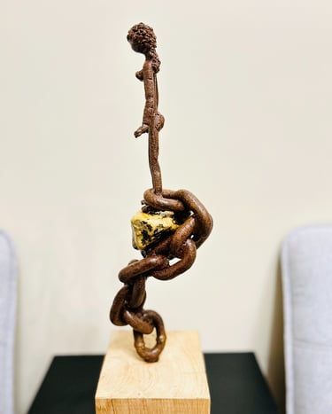 Iron sculpture with stone on wooden pedestal