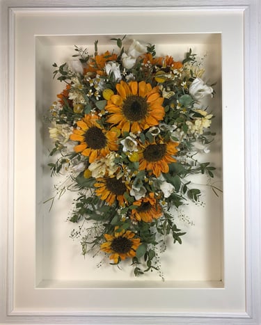 a Trailing view Style bouquet of flowers in a ridged white frame