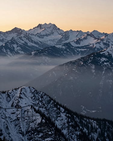 A breathtaking landscape photograph of the North American Rockies at dawn, with sharp focus on the snow-capped peaks and a soft pale mist in the valleys, demonstrating high dynamic range photography.