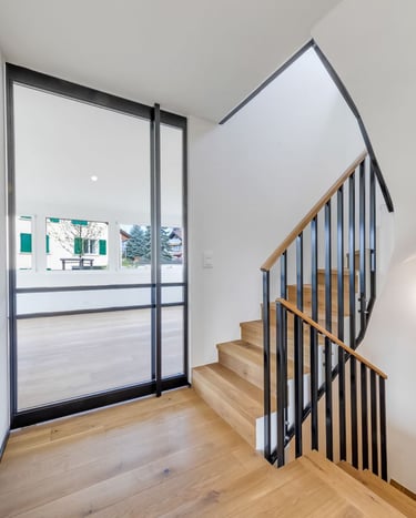modern staircase with wood steps and black metal railing in bright hallway