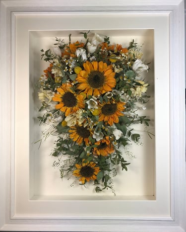 a Trailing view Style bouquet of flowers in a ridged white frame