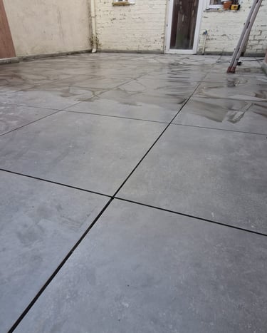 Terrasse extérieure en dalles de béton gris clair posées sur lit de mortier, aspect brut et contempo
