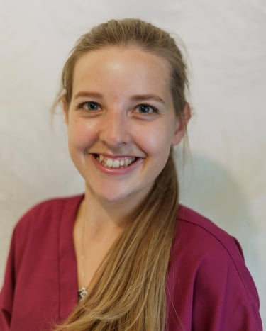 Profile of a young woman with long brown hair wearing burgundy scrubs