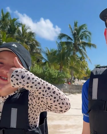 two boys in life jackets standing in the sand