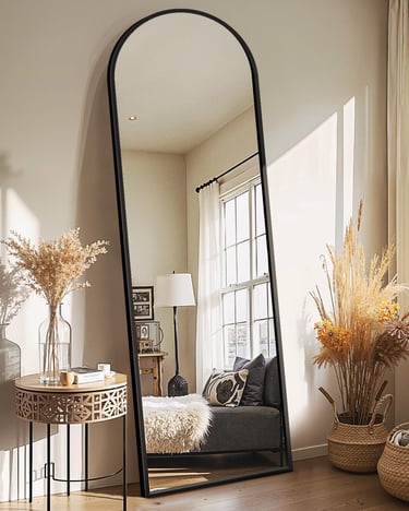 Large arched full-length floor mirror with black metal frame styled in a modern cozy living room.
