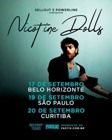 Plano médio de Sam Cieri, vocalista do Nicotine Dolls, sentado e posando contra uma parede azul