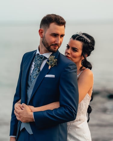 una novia y un novio en una playa abrazándose en el día de su boda