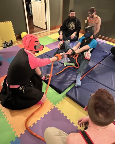 a group both in and out of pup hoods playing tug of war.