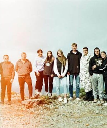 Group of young people standing together on a hill, symbolizing community and friendship.