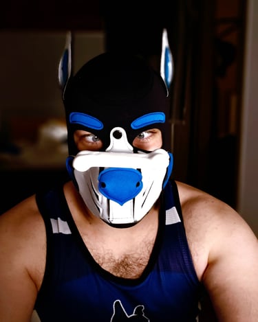 Man in a pup mask with a toy balancing on his nose.