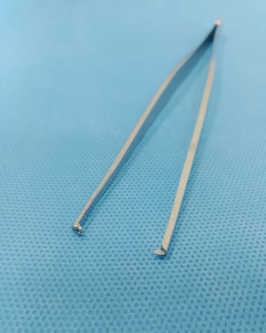Pinça dente de rato sobre tecido azul estéril, usada para segurar tecidos firmes.
