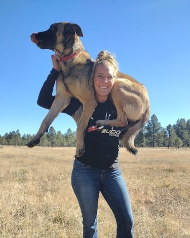 a woman holding a dog in a field