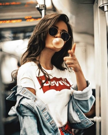 a woman in a white shirt and sunglasses blowing bubbles