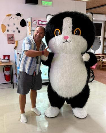 Guest posing with CatWorld cat mascot inside Samui cat cafe