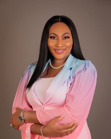 Professional portrait of a smiling woman wearing a pink and blue ombre blazer and pearl necklace.