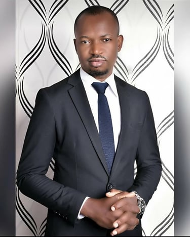 Professional portrait of a man wearing a black business suit and blue tie against a patterned background.
