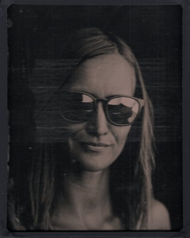 jeune femme blonde posant dans la pénombre avec des lunettes de soleil