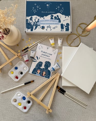 Kit créatif Paint Your Partner avec toiles, pinceaux, peintures et chevalets disposés sur une table.