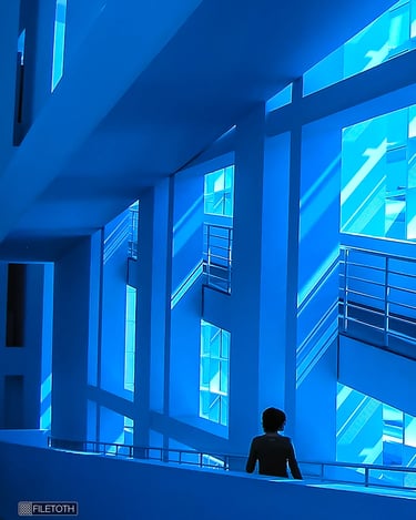 Interior view of MACBA’s atrium where soft daylight filters through the glazed façade, coloring white walls blue.