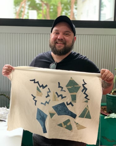A person with a brown beard and light skin holds a banner with zig zag shapes.