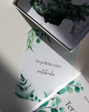 Afirmacijų kortelės su žaliais lapais; matoma kortelė su tekstu „Aš priimu save netobulą"