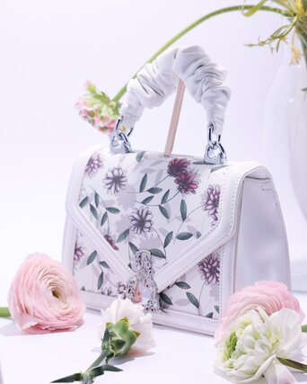 White bag with a floral pattern surrounded by flowers