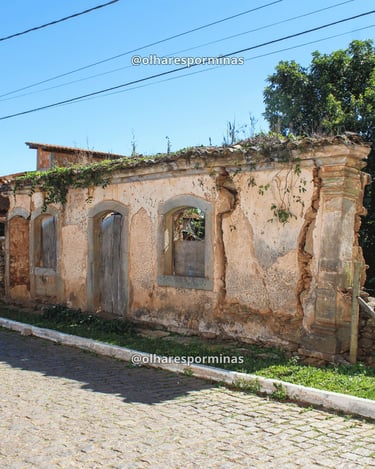 Casarão antigo em Itatiaia, distrito de Ouro Branco MG, com ruínas históricas e rua de pedra sob céu