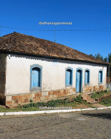 Casa colonial em Itatiaia, distrito de Ouro Branco MG, com janelas azuis, telhado antigo e rua de pe