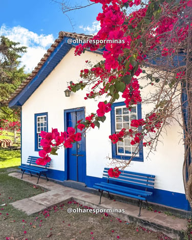 Casa colonial na Vila do Biribiri, em Diamantina, com janelas azuis e flores vermelhas